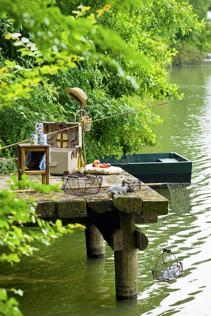 Angelutensilien und Picknickkoffer auf einem Steg