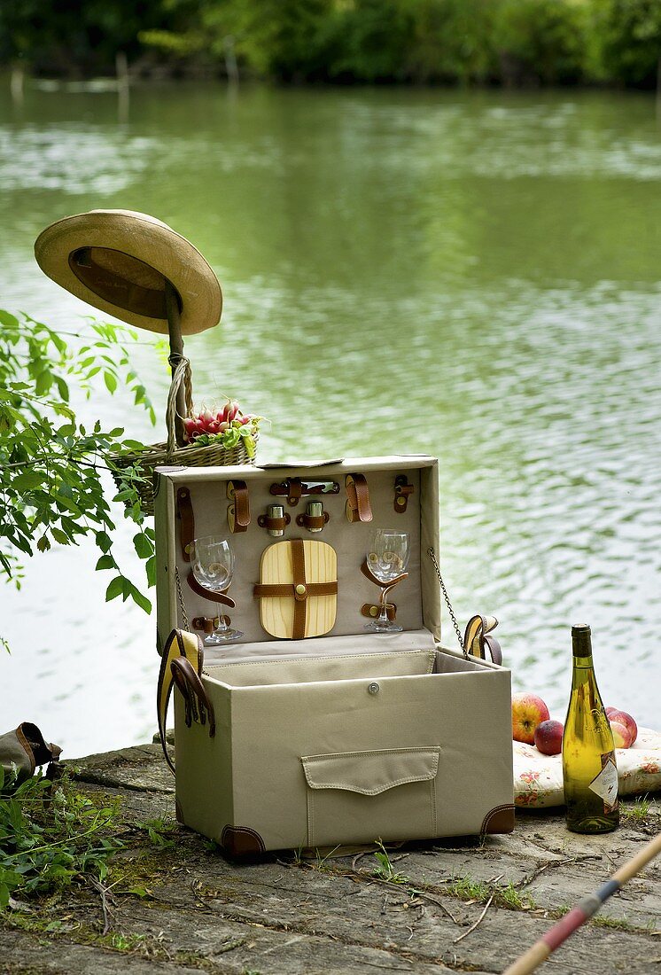 Picknickkoffer auf einem Steg und eine Flasche Weißwein