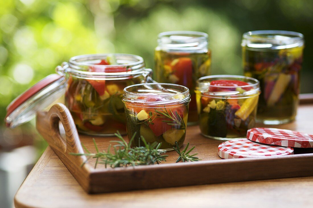 Several jars of pickled summer vegetables on tray