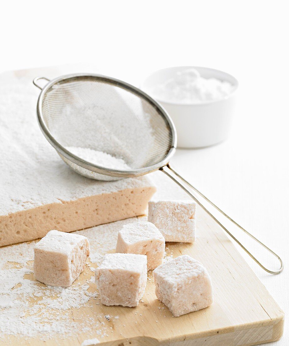 Selbstgemachte Marshmallows mit Puderzucker auf Schneidebrett