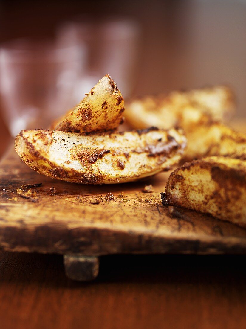 Spicy potato wedges on chopping board