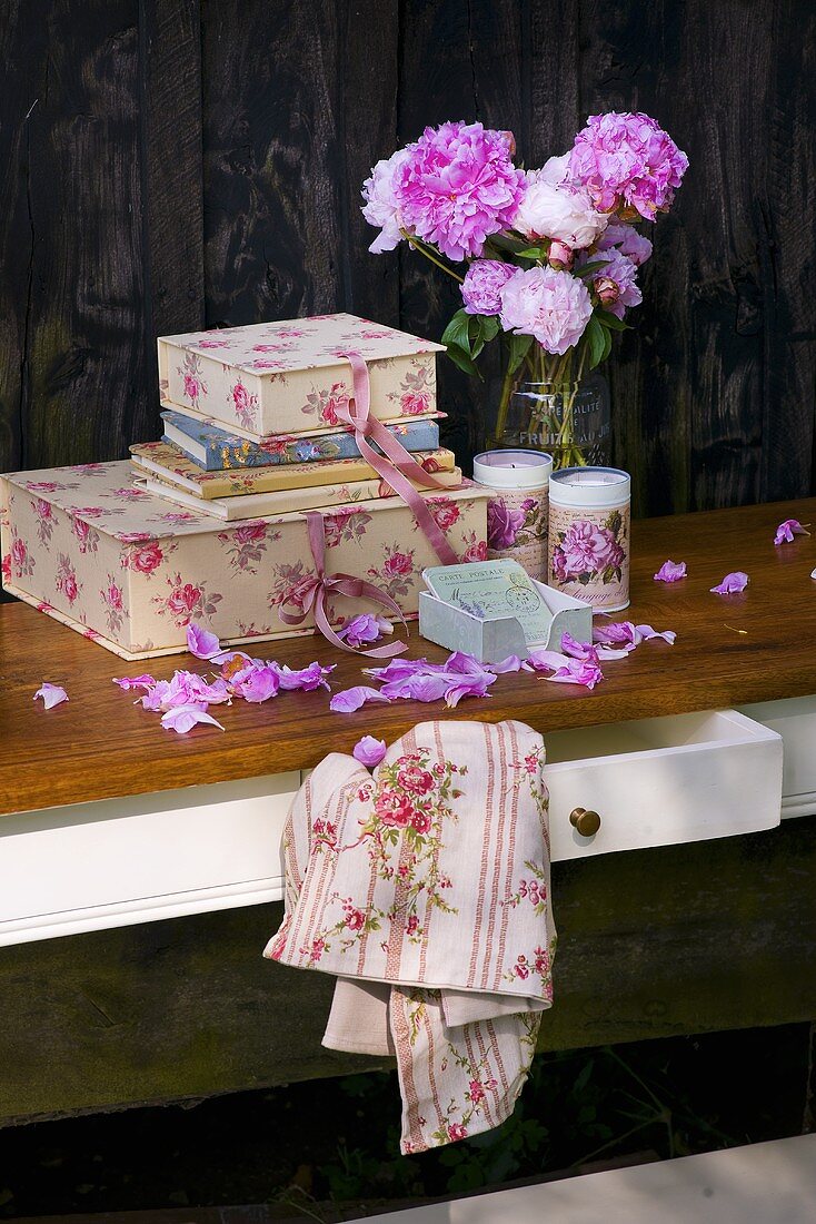 Boxes, books, peonies and candles on a table