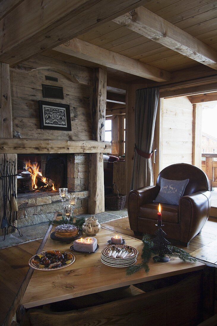 Weihnachtsbäckerei und Tee auf Wohnzimmertisch vor brennendem Kamin im Landhaus