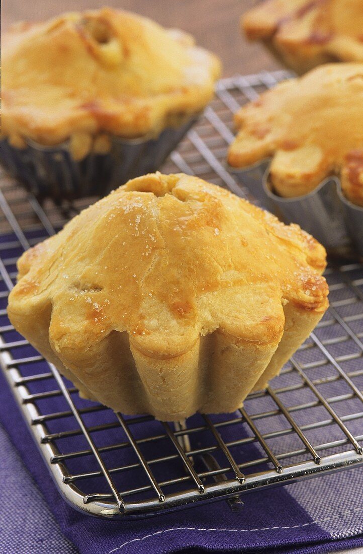 Individual apple and pear pies on cake rack