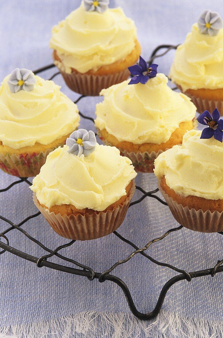 Mehrere Cupcakes mit Buttercreme und Blütendeko