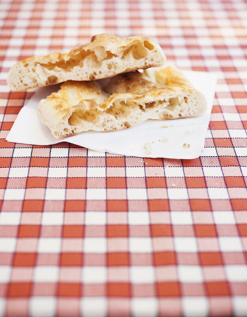 Pieces of focaccia on napkin on checked tablecloth