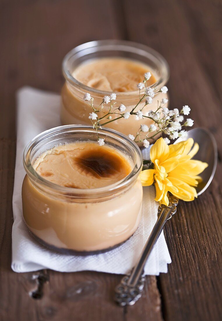 Crème brûlée in glass jars on wooden table