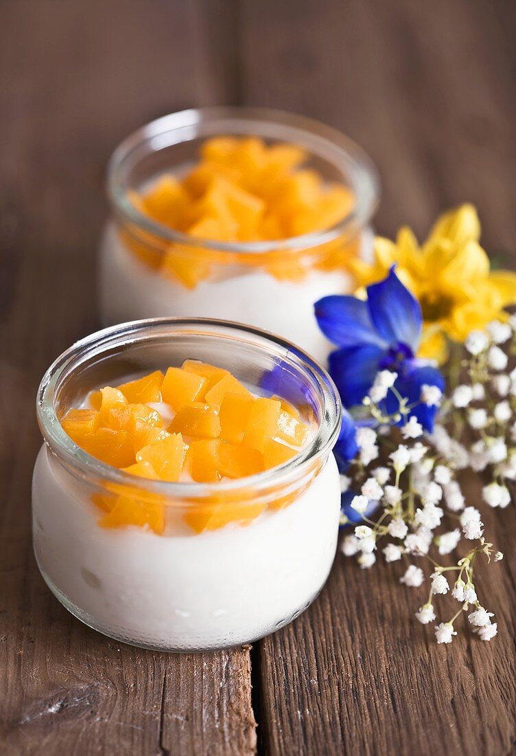 Joghurt mit Pfirsichstückchen in Gläsern auf Holztisch