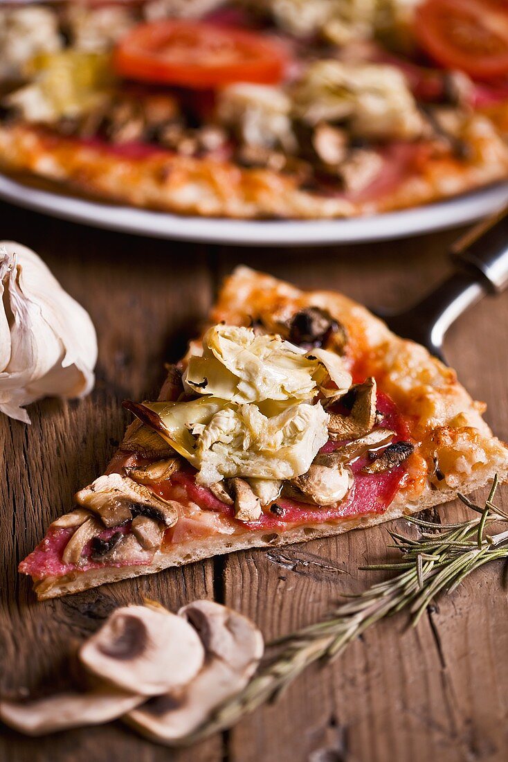 Pizza mit Salami und Artischocken auf Holztisch