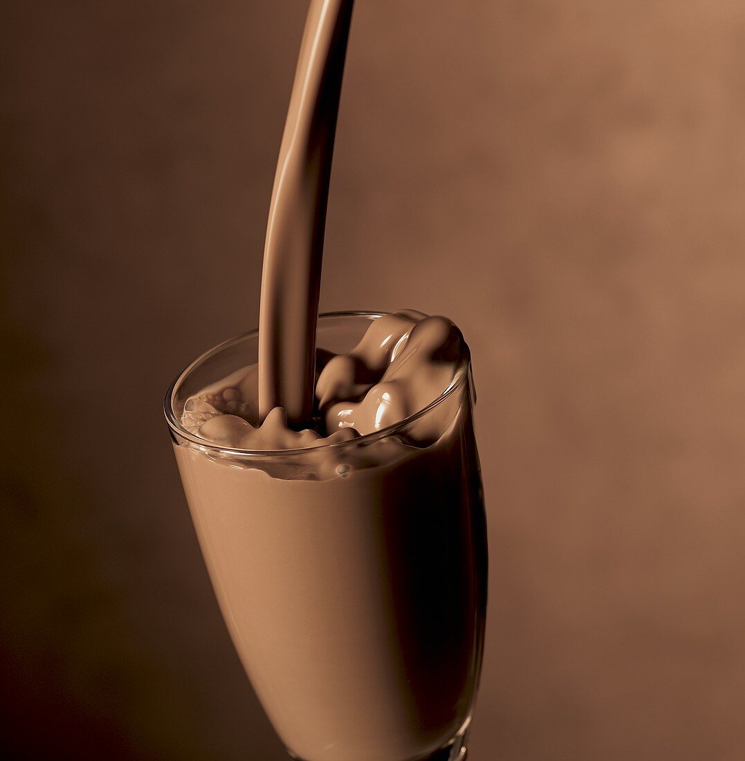 Schokoladenmilch in ein Glas gießen