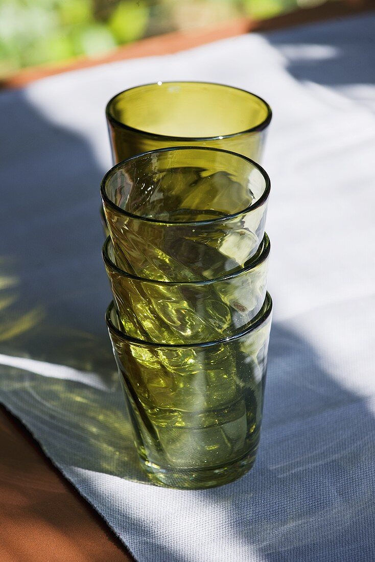 Green drinking glasses, stacked, on table out of doors