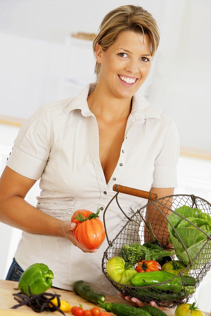 Woman holding wire basket of organic vegetables