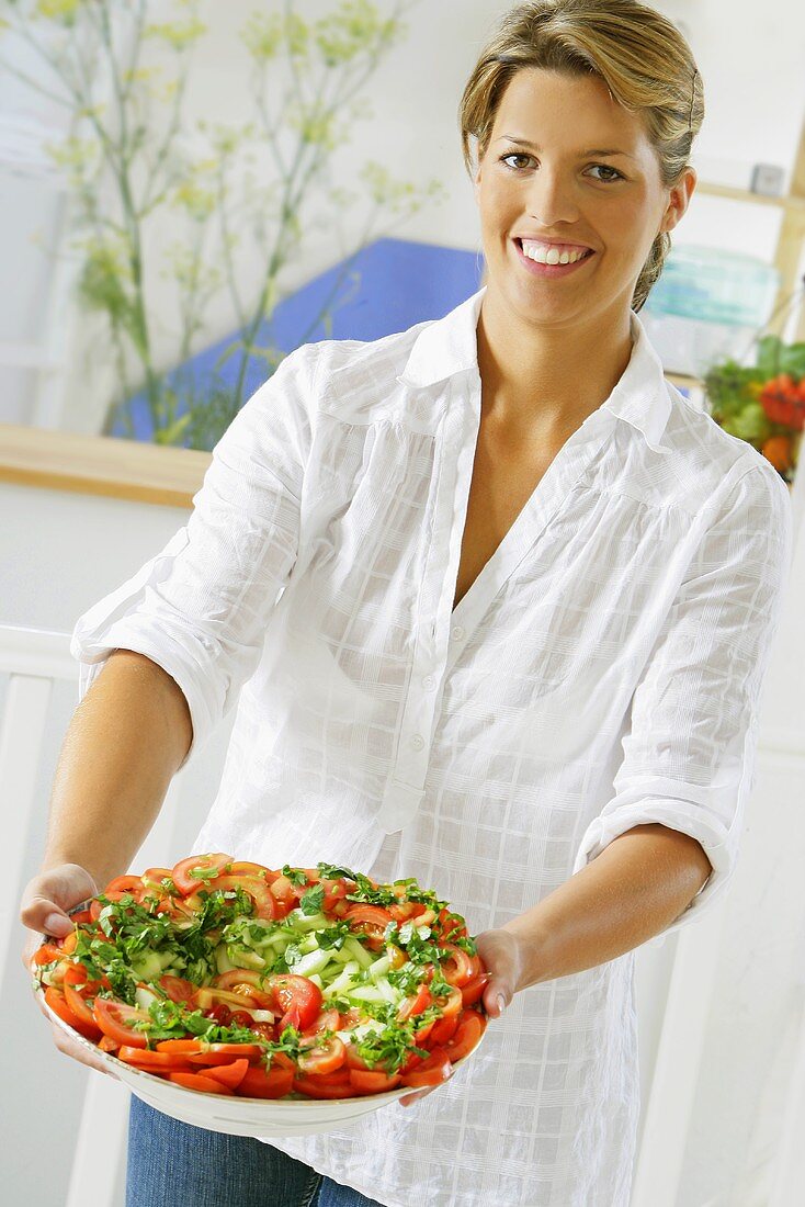 Frau hält Platte mit Tomatensalat