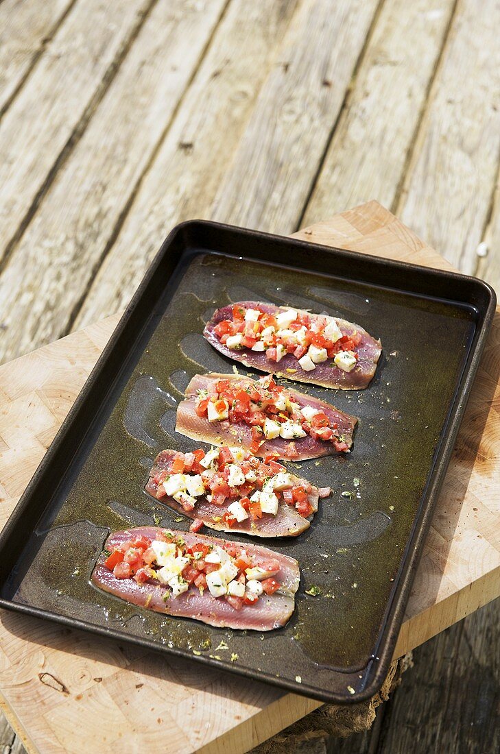 Sardines with cheese and tomato stuffing on a baking tray