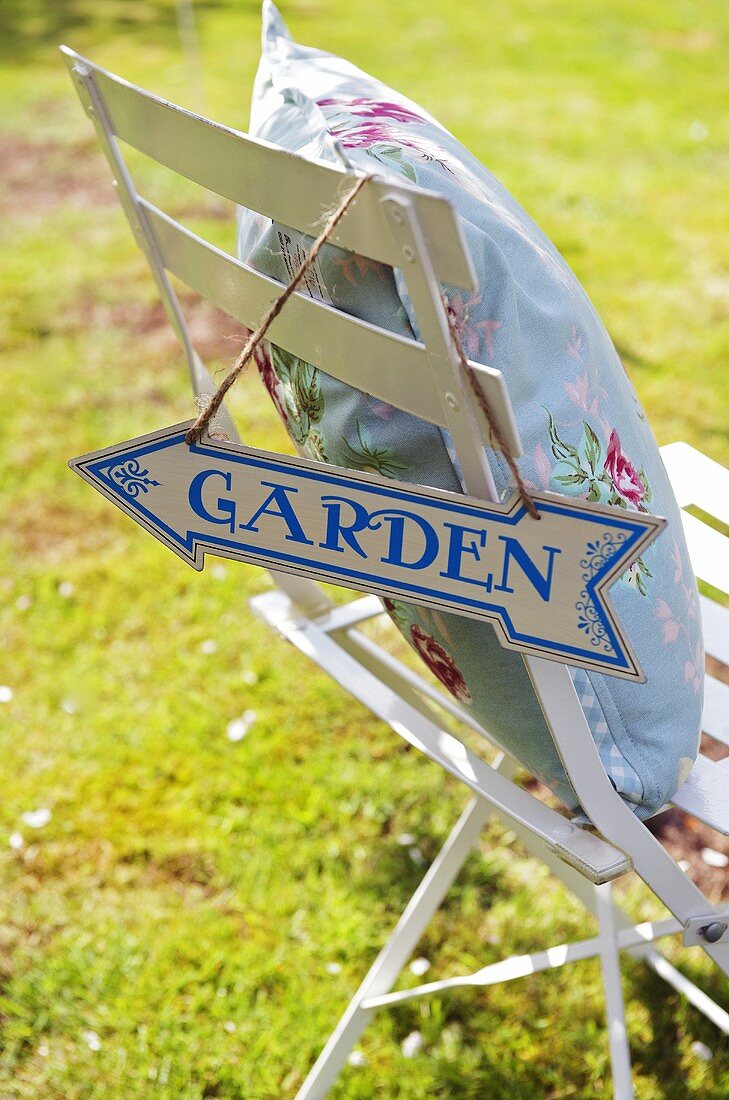 Chair with cushions and signpost to garden