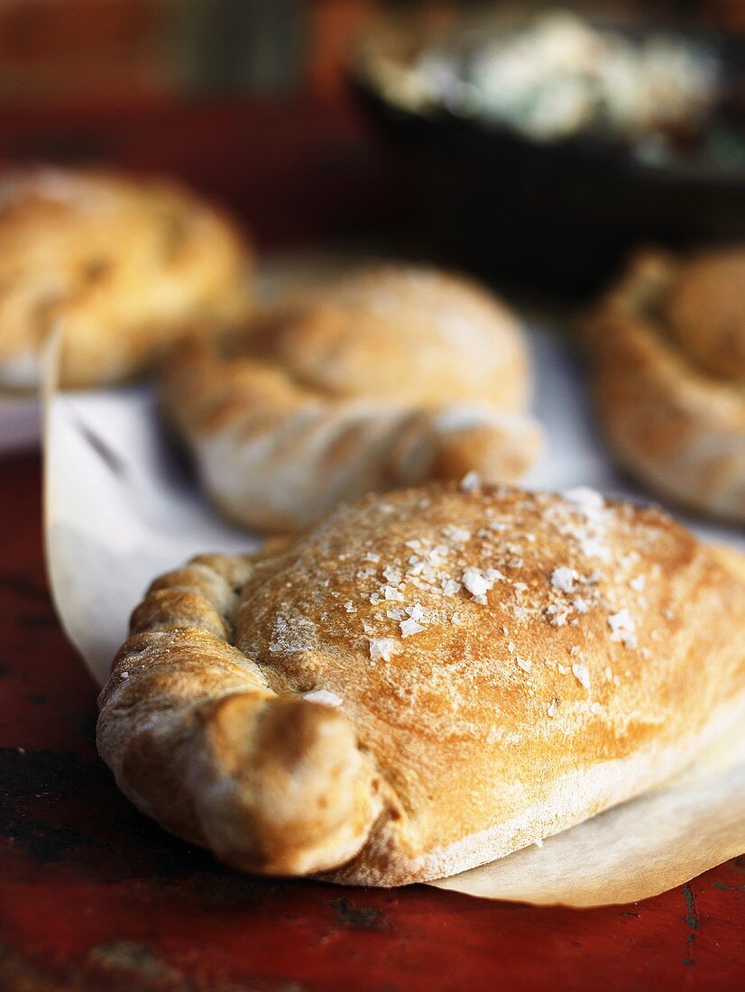 Several calzone on baking parchment