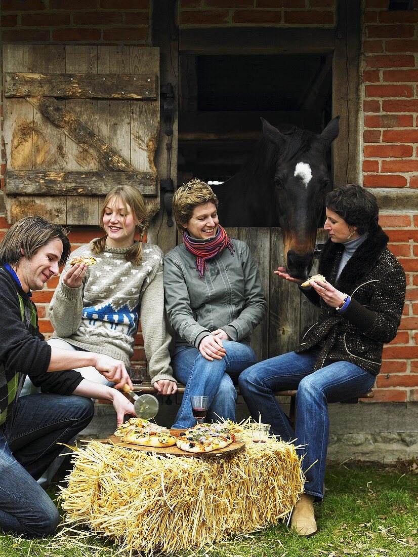 People eating focaccia outside stable