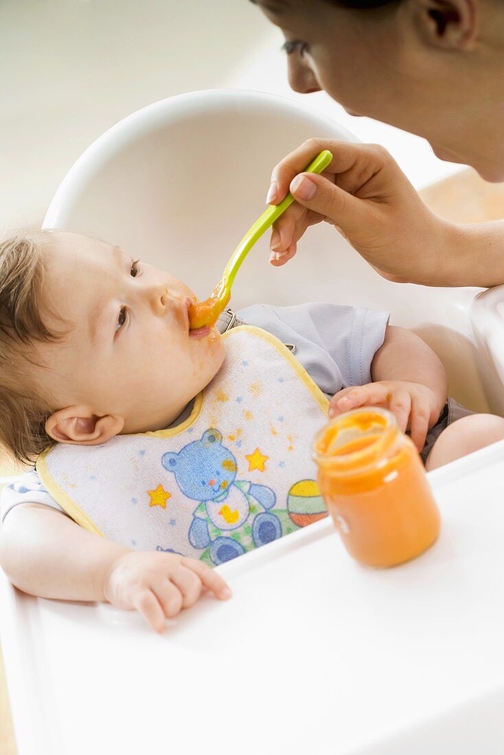 Mother feeding her baby with baby food