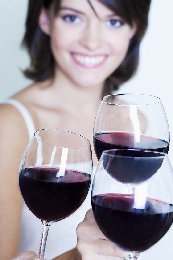 Three glasses of red wine, young woman in background