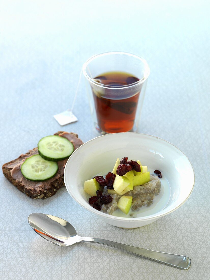 Porridge mit Früchten, belegtes Brot mit Streichwurst und Tee