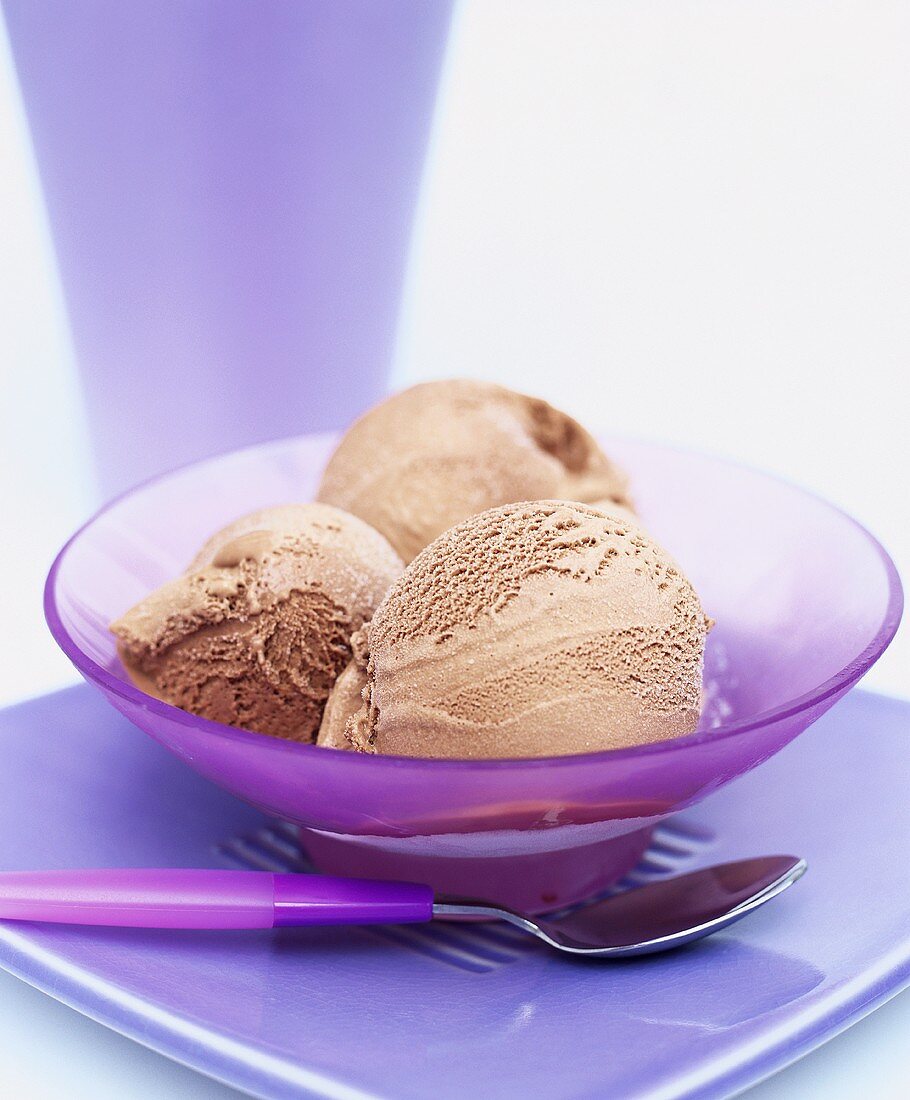 Three scoops of chocolate ice cream in a glass bowl