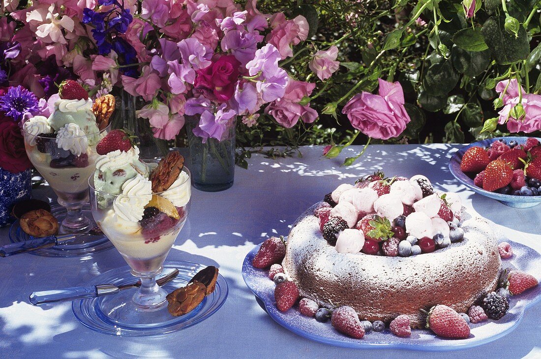 Tisch mit Kuchen, Dessert und Blumen im Freien
