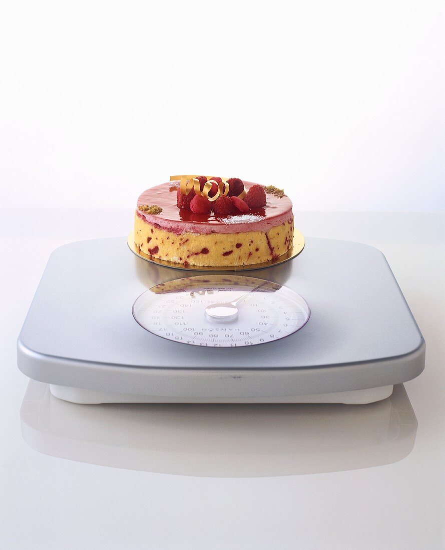 A berry cream cake on bathroom scales