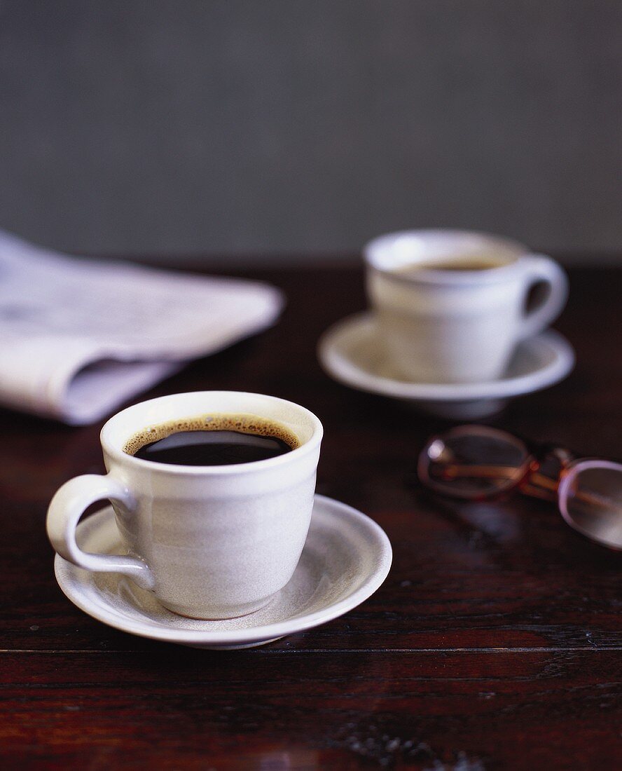 Two cups of coffee and newspaper