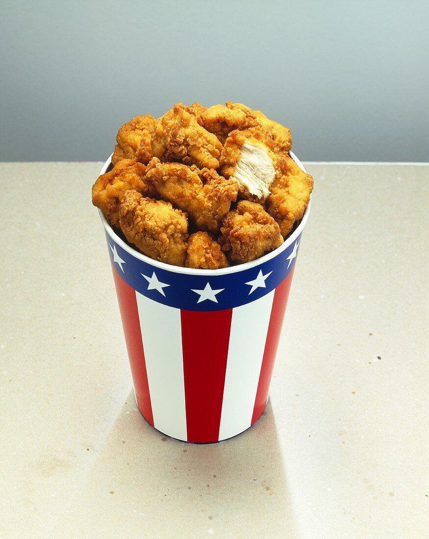 Chicken nuggets in paper cup with US … – License Images – 400887 StockFood