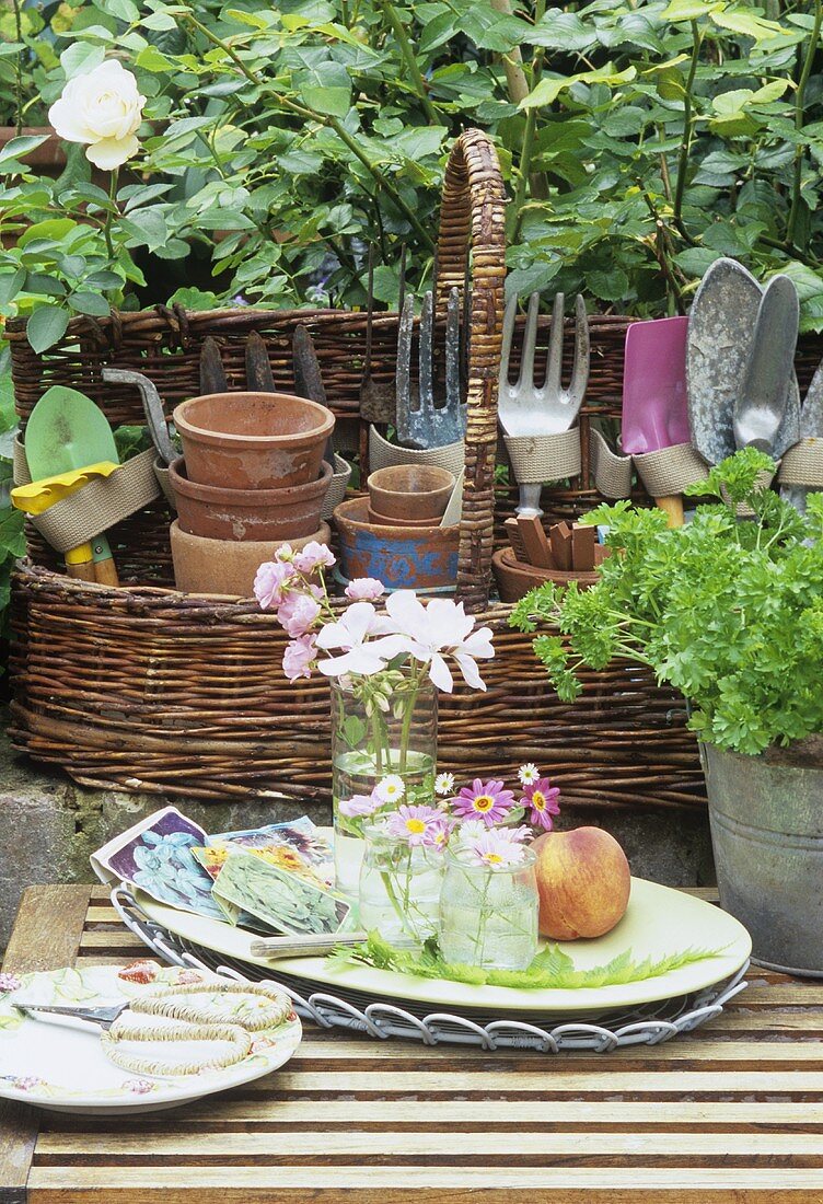 Still life: flowers, basket of terracotta pots & garden tools