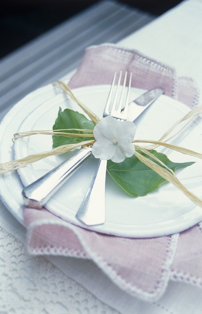 Place-setting with cutlery, decorated with raffia & flower