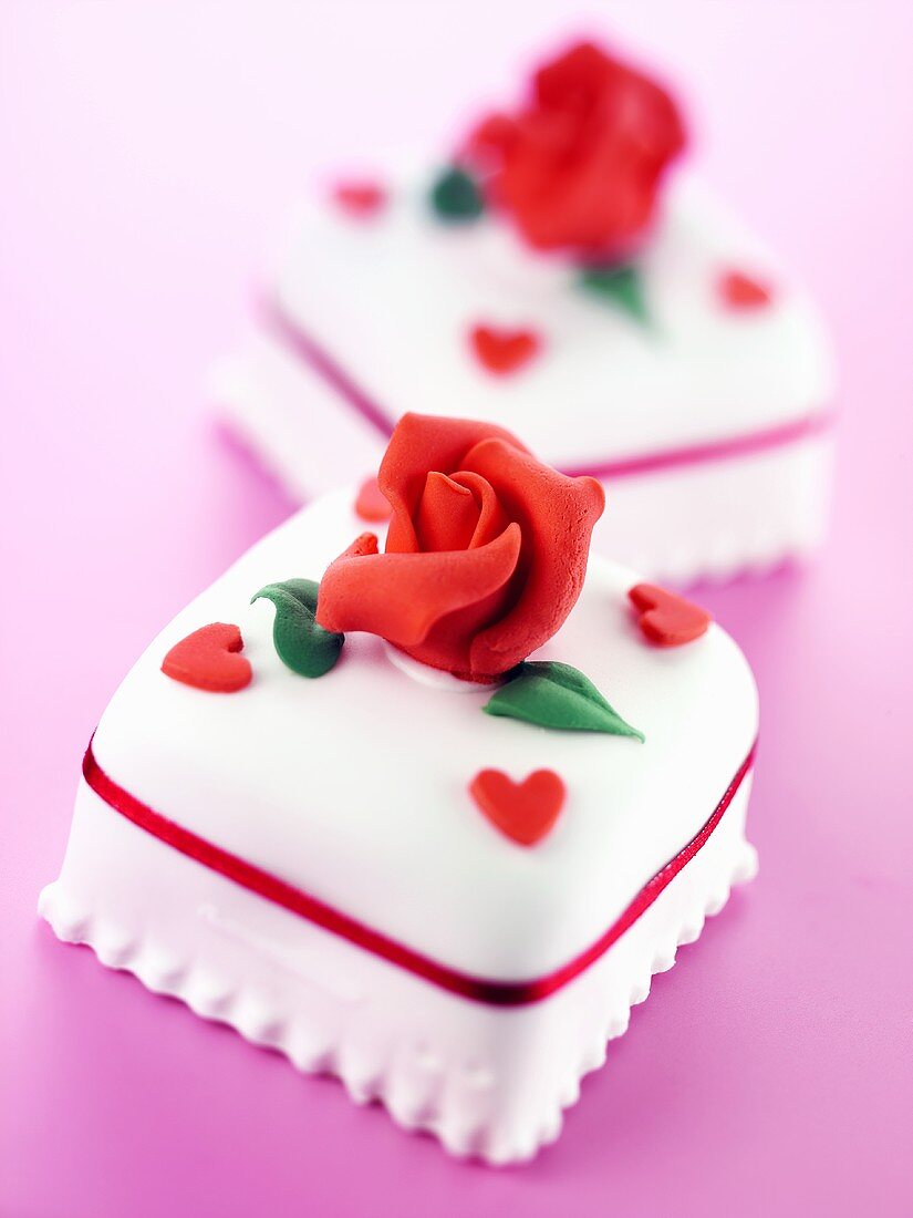 Two iced petit fours with marzipan roses and tiny hearts