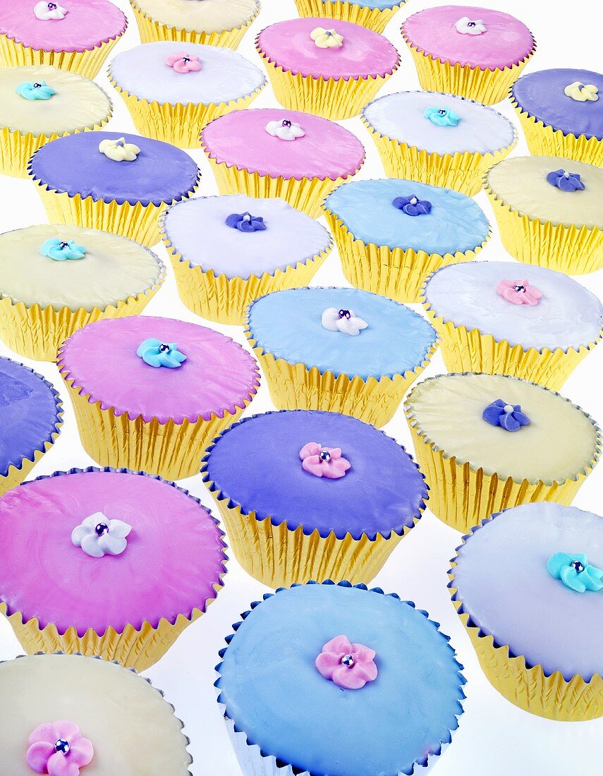 Many muffins with pastel-coloured decorations