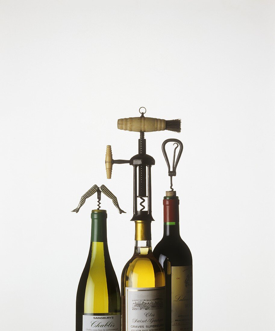 Drei Weinflaschen mit Korkenziehern
