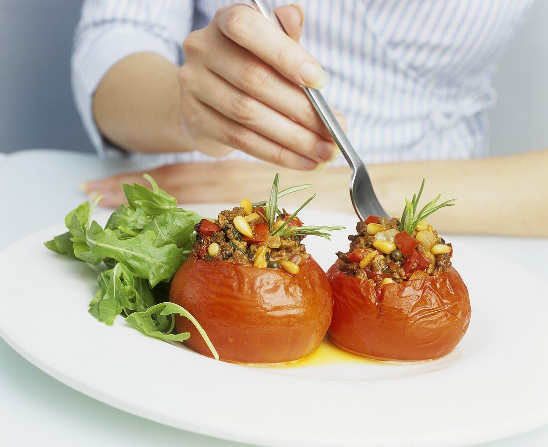 Junge Frau isst gefüllte Tomaten