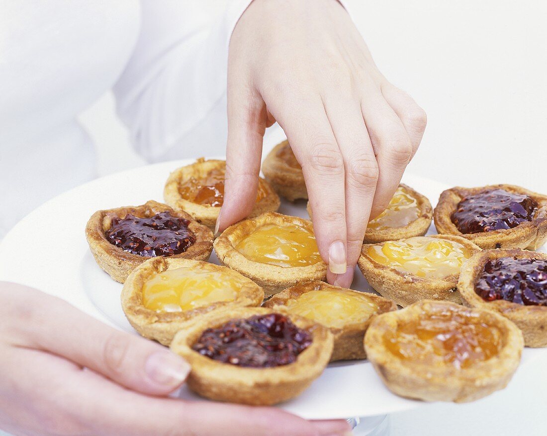 Frau hält Teller mit Jam-Tarts (Marmeladentörtchen)