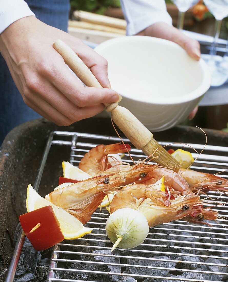 Garnelenspiesse auf dem Grill werden bepinselt