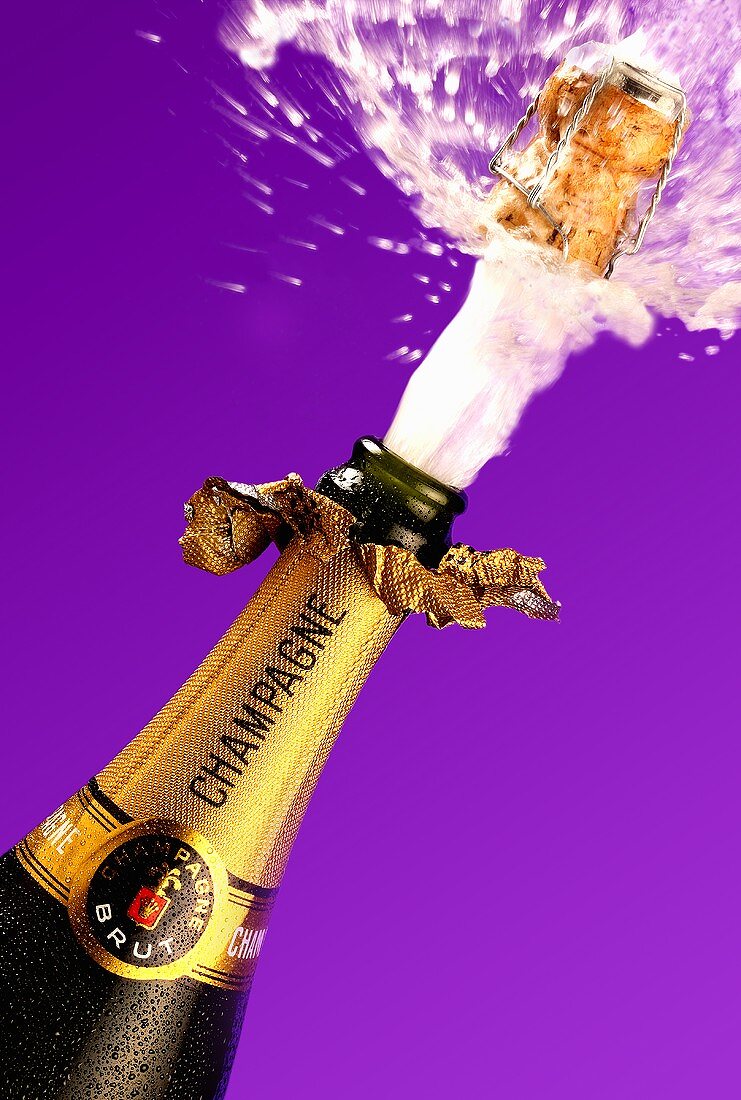 Cork flying out of champagne bottle, purple background
