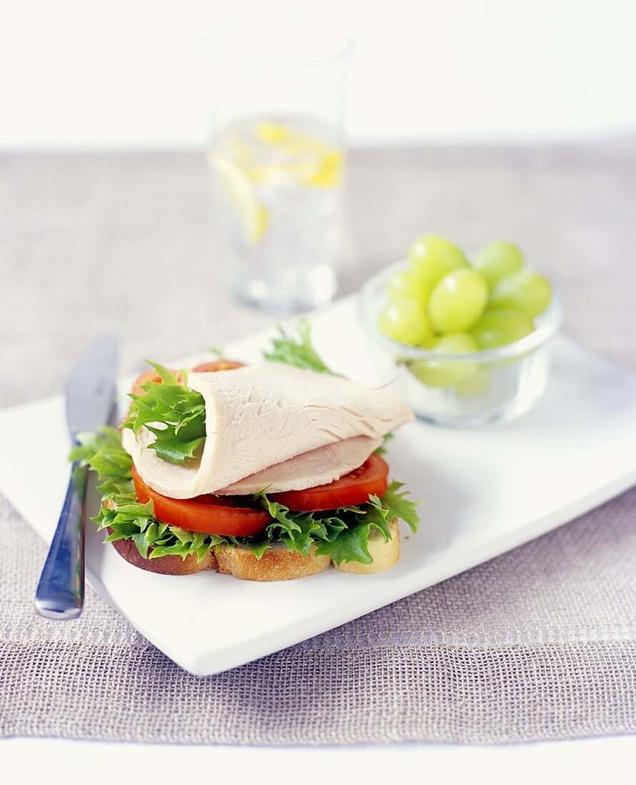 Belegtes Brot mit Putenbrustaufschnitt, Salat und Tomate