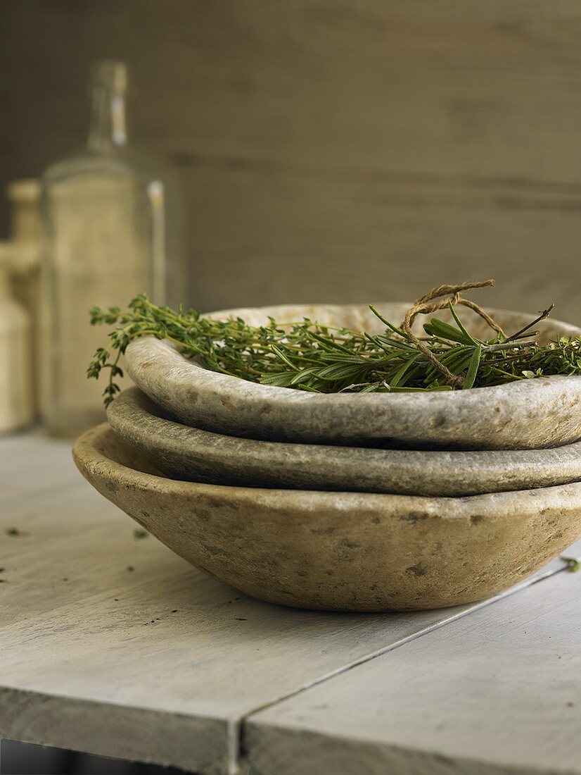 Various herbs in stacked stone bowls