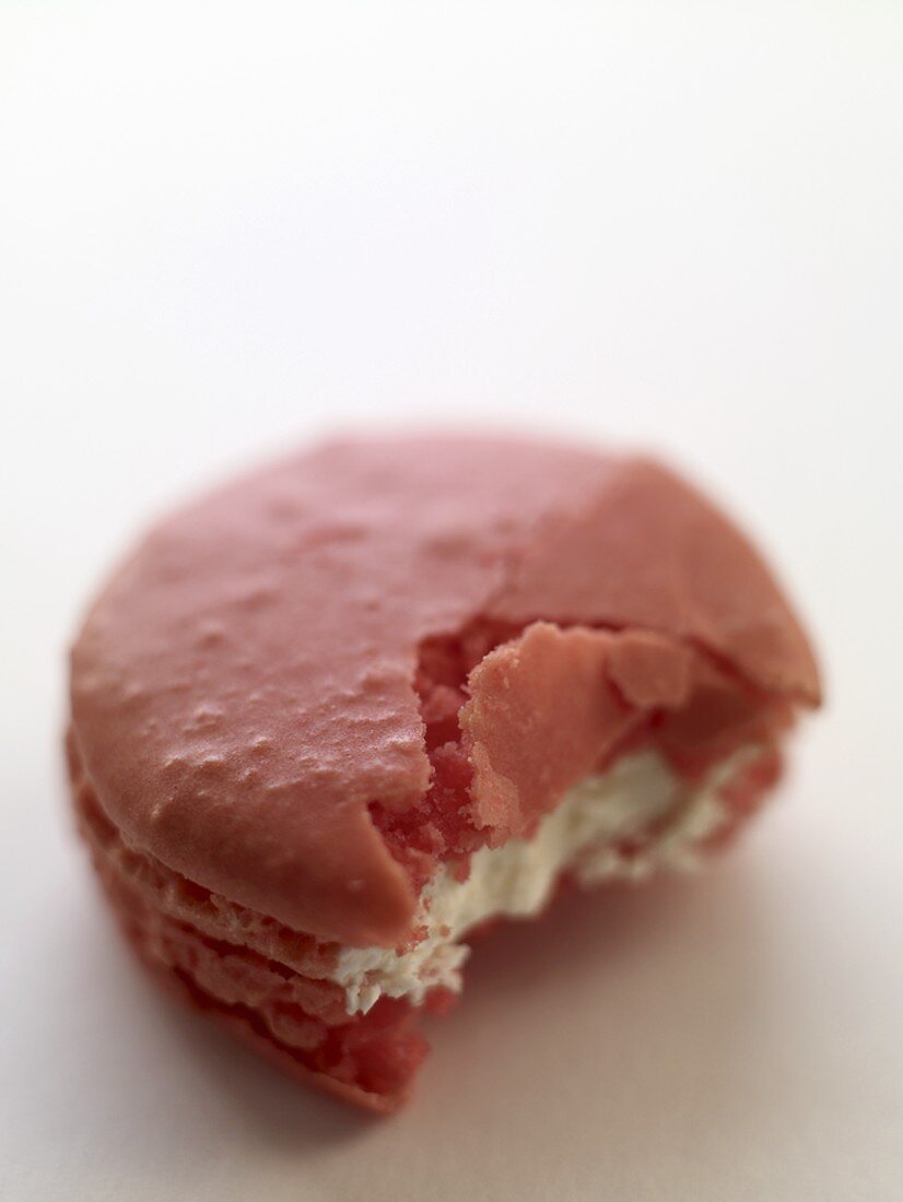 Pink macaron (small French cake), partly eaten