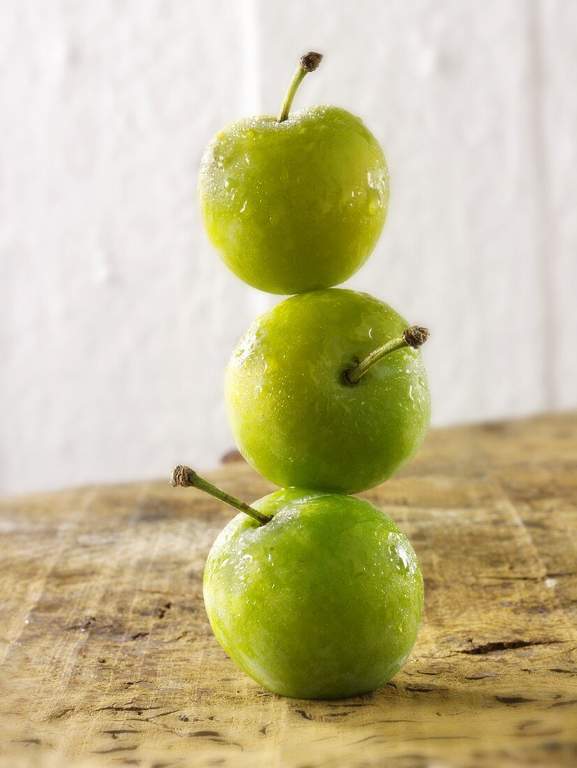 Three greengages, in a pile, one on top of the other