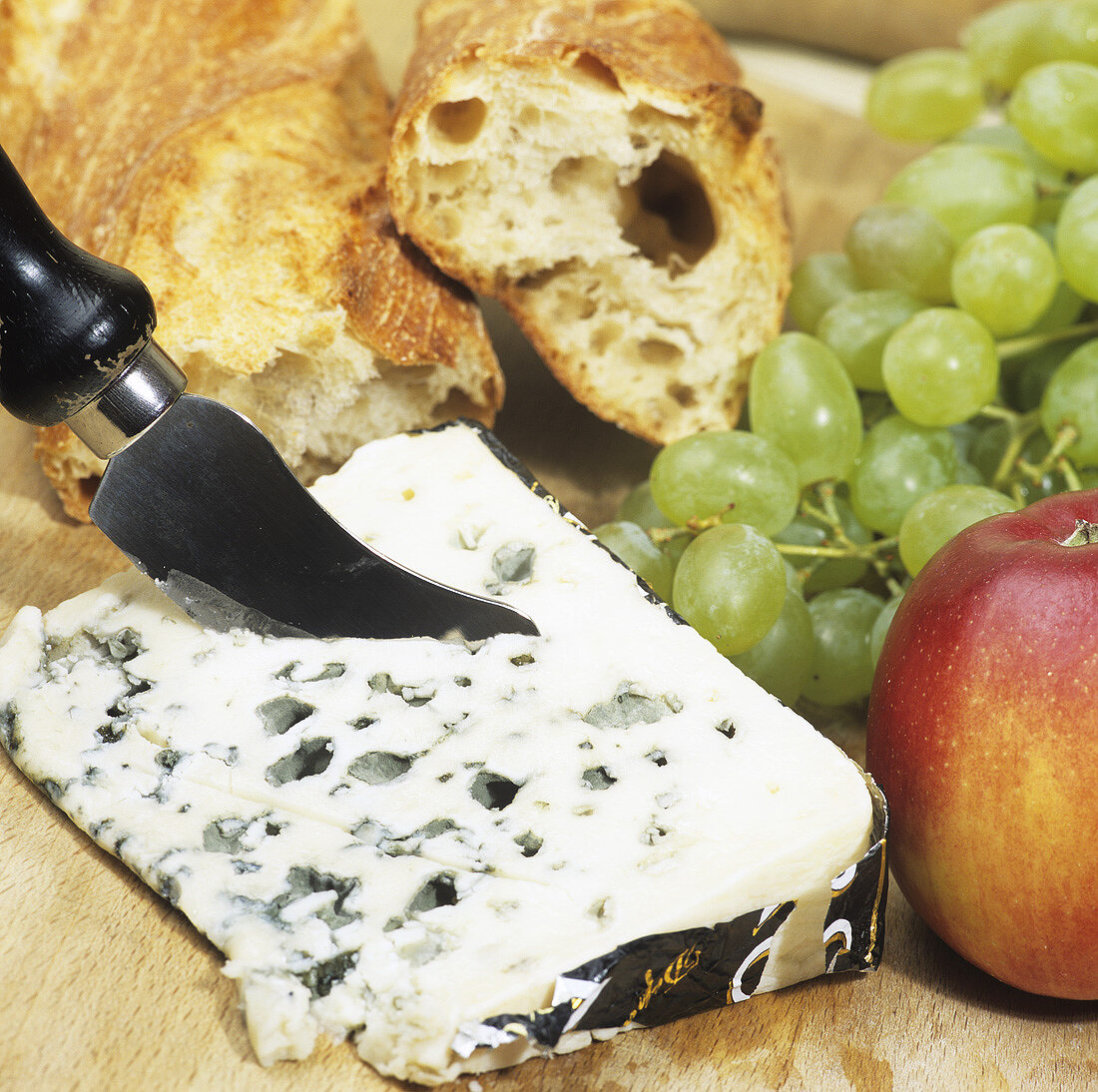 A piece of Roquefort with fruit and baguette