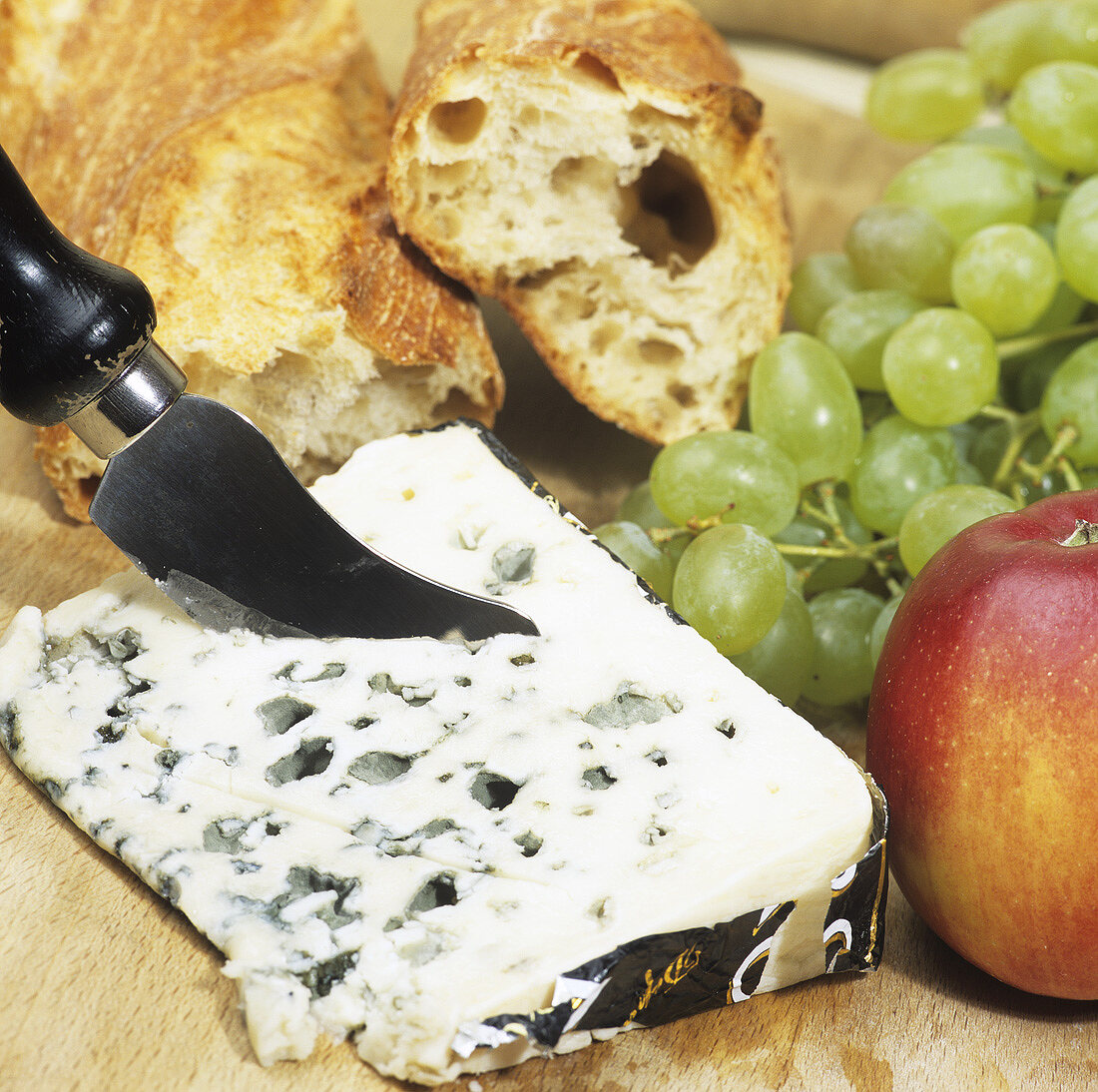 Ein Stück Roquefort mit Obst und Baguette