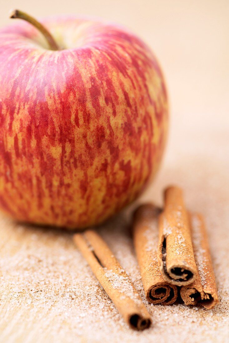 Ein Apfel, brauner Zucker und Zimtstangen