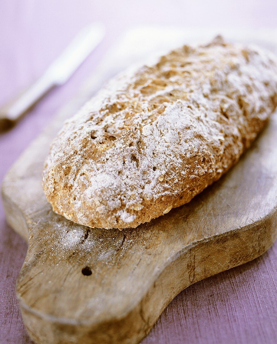 Long loaf of bread on wooden board