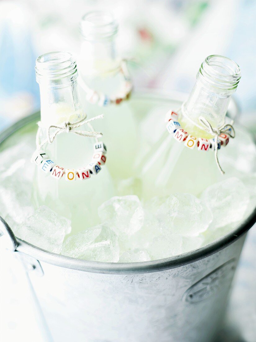 Three bottles of lemonade in an ice bucket