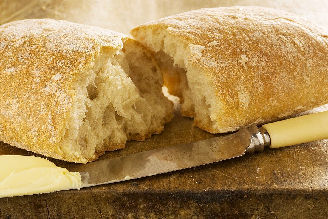 Halbiertes Ciabatta mit Messer und Butter