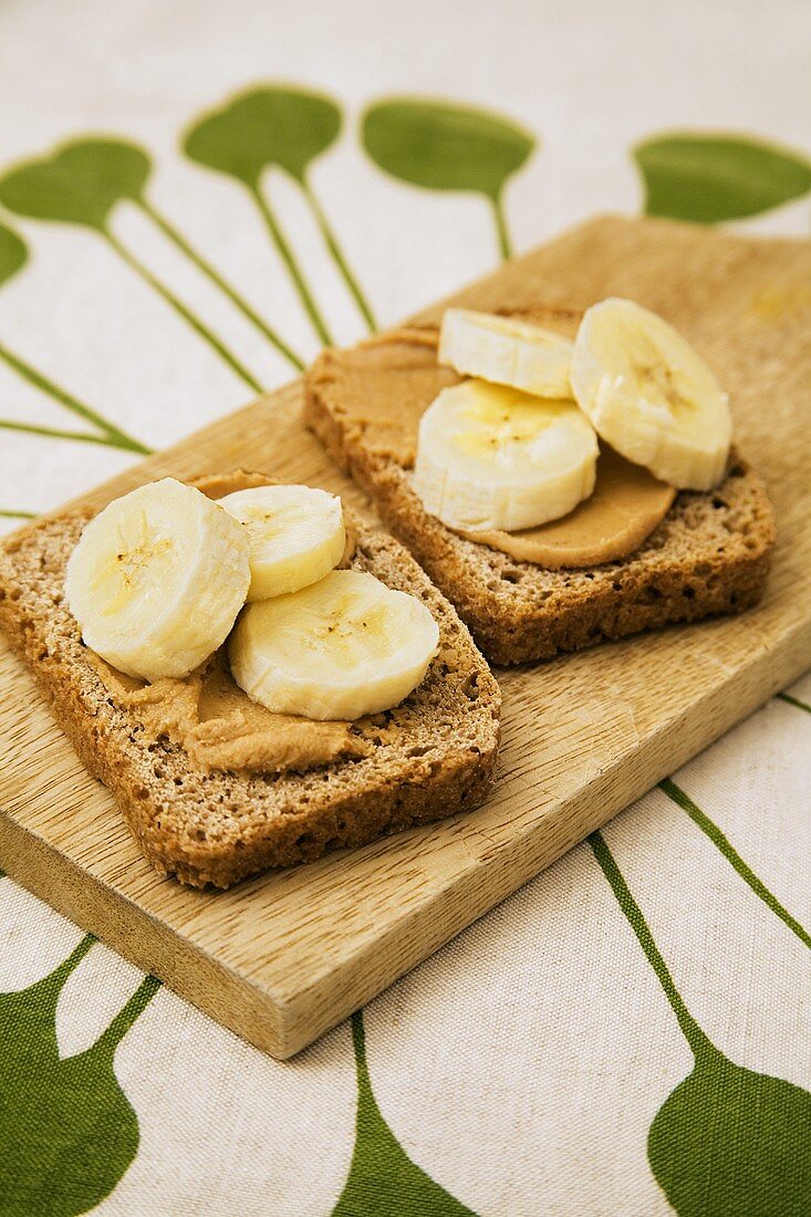 Two slices of rye bread topped with peanut butter & bananas