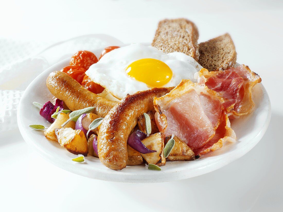 English breakfast: sausages, bacon, egg, potatoes, tomatoes